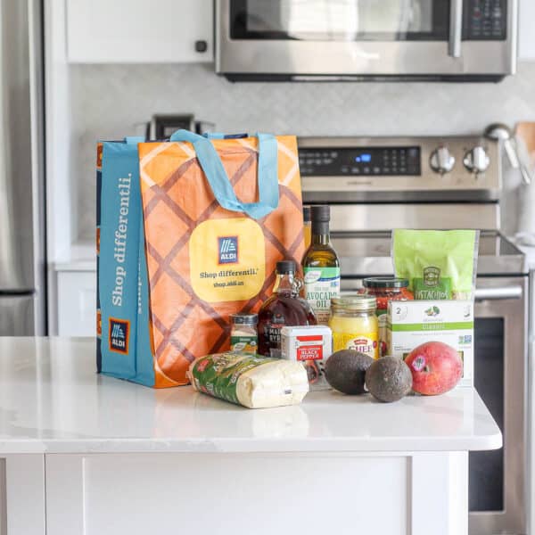 An aldi bag on the counter in a kitchen with a variety of groceries.