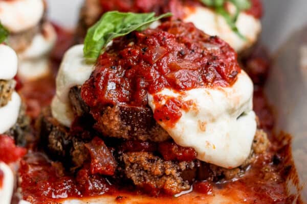 Side angle of a stack of baked eggplant parmesan still in the baking dish.