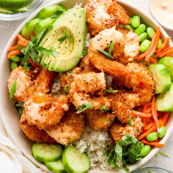 Top down shot of a bang bang shrimp rice bowl with avocado, cucumber, carrots, edamame and cilantro.