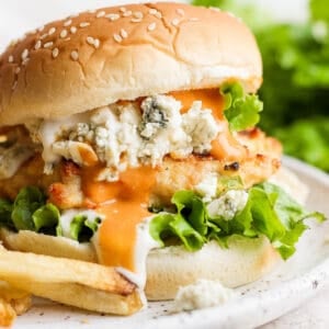 A buffalo chicken burger on a bun with butter lettuce, buffalo sauce and blue cheese.