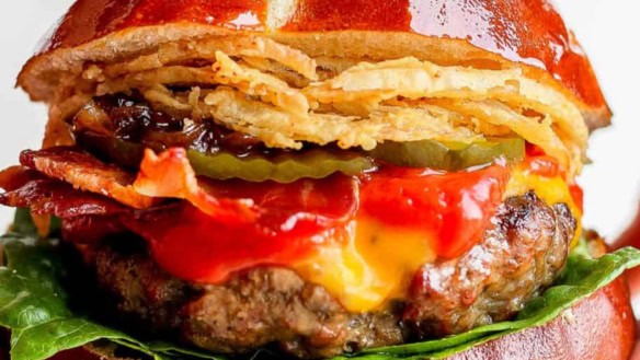 Burger with cheese, ketchup, pickles and onion straws