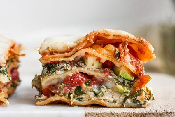 A piece of vegan lasagna on a marble and wood board.