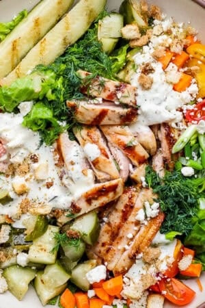 A big bowl of a dill pickle chicken chop salad with grilled pickles, chicken thighs, carrots and dill.