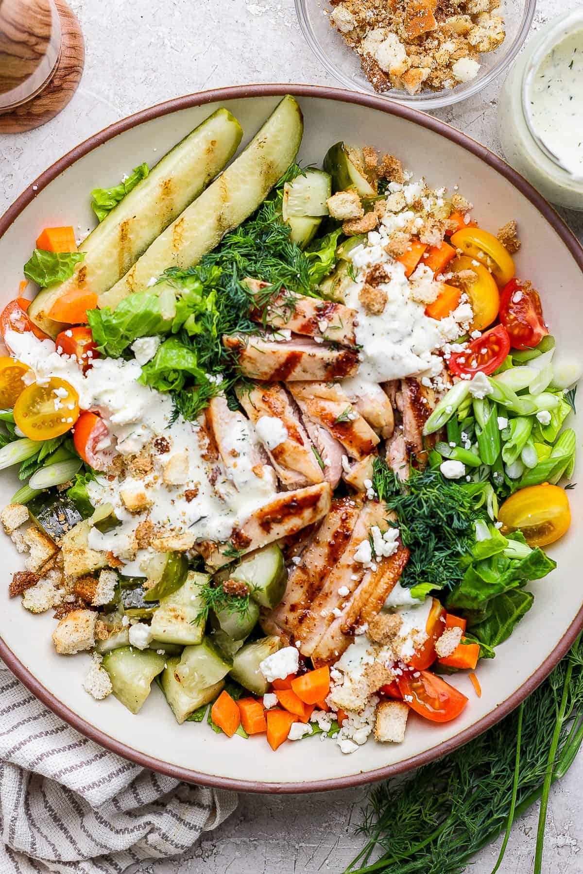 A dill pickle chicken salad with dressing and grilled pickles on the side.