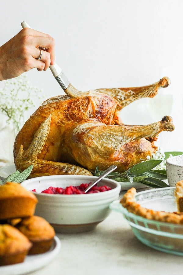 Someone basting a deep fried turkey on a platter.