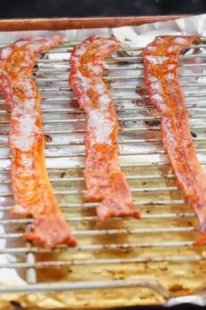 Bacon a foil lined baking sheet with a wire rack on top of a grill with the bacon cooked and bubbly.