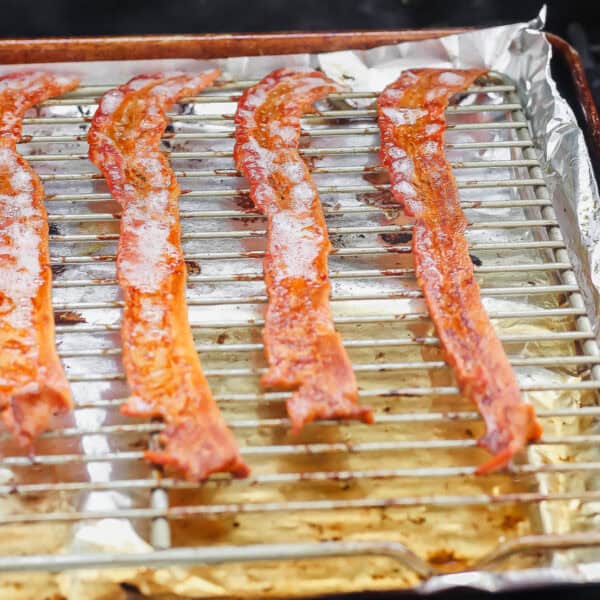 Bacon a foil lined baking sheet with a wire rack on top of a grill with the bacon cooked and bubbly.