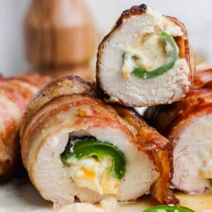 Top pieces of grilled jalapeno popper chicken cut in half on a plate with cheese oozing out.