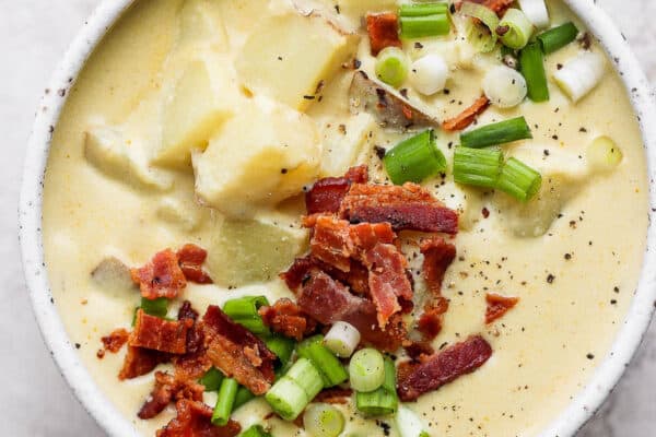 A bowl of loaded baked potato soup with bacon and green onion on top.