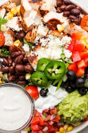 A bowl filled with a santa fe salad and southwest dressing.