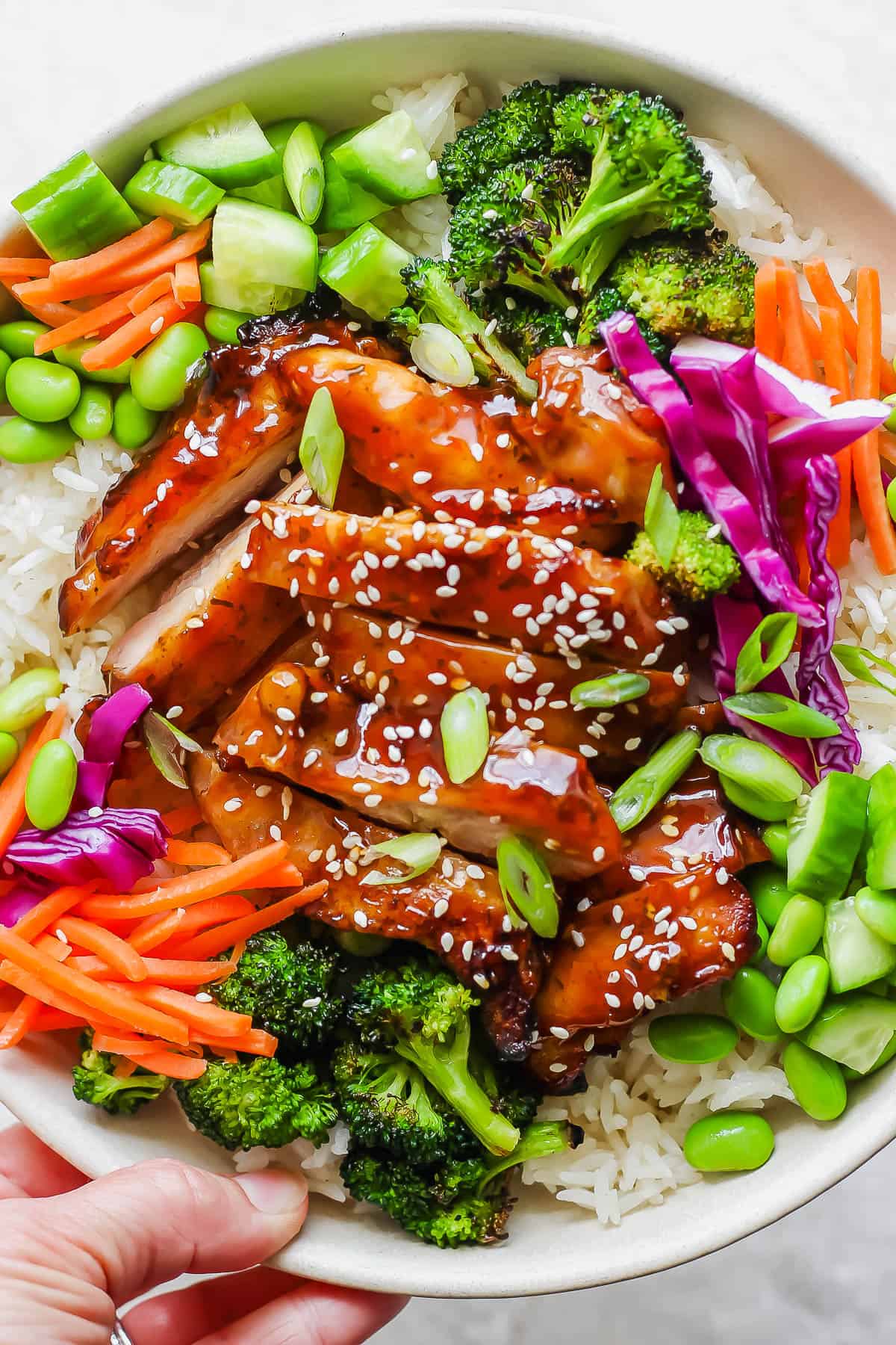 Teriyaki chicken in a rice bowl with fresh vegetables.