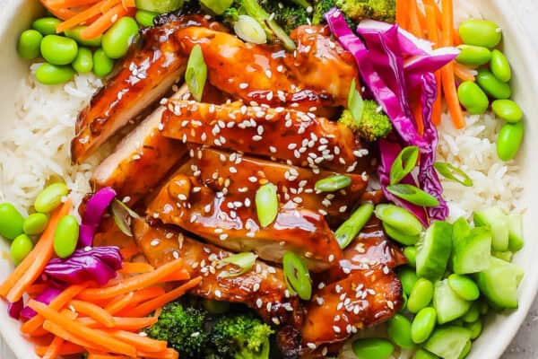 Sliced teriyaki chicken with sesame seeds and fresh vegetables.