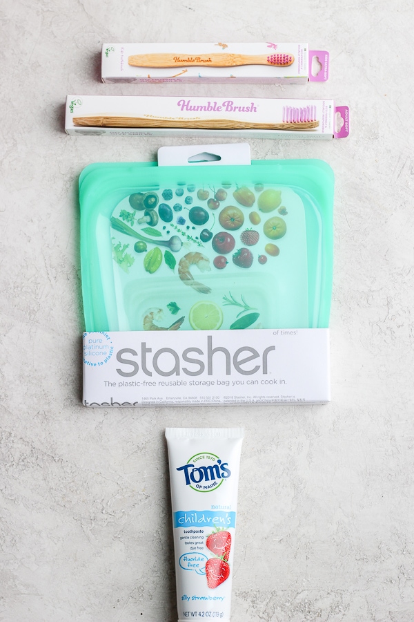 Two packs of wooden toothbrushes, a stasher bag in the packaging and a tube of Tom\'s toothpaste.