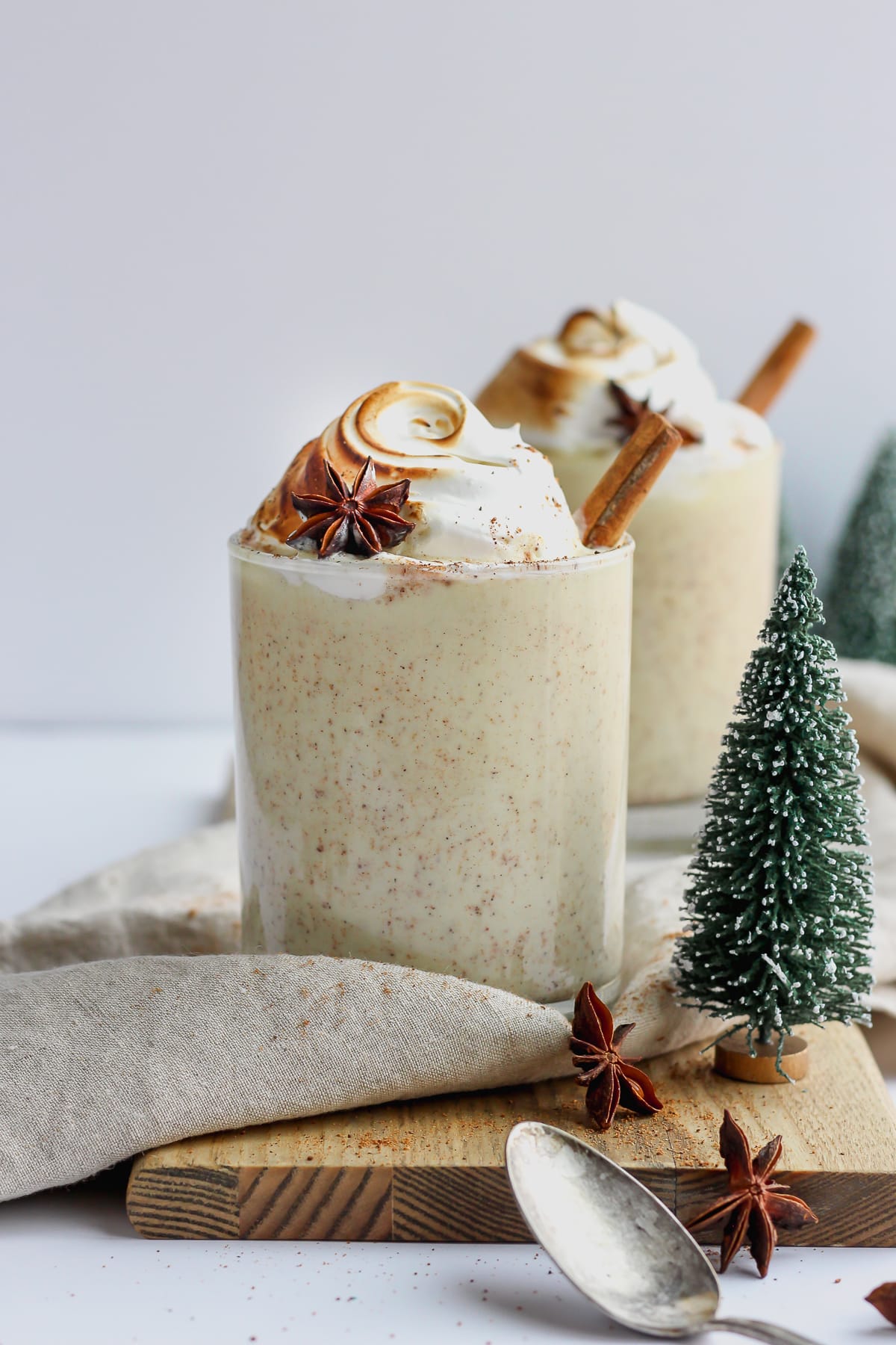 Two glasses of egg nog with cinnamon sticks out the top.