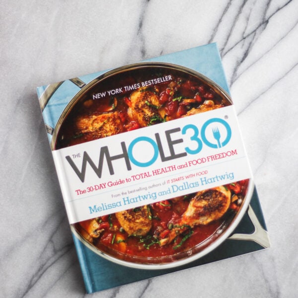 The book Whole30 The 30 Day Guide to Total Health and Food Freedom on a marble counter top.